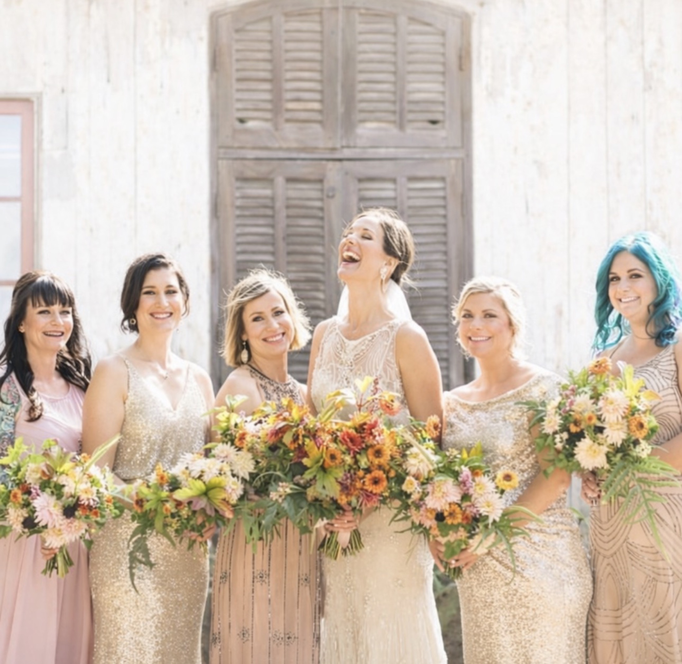 Bridal party holding colorful bouquets in bright window light