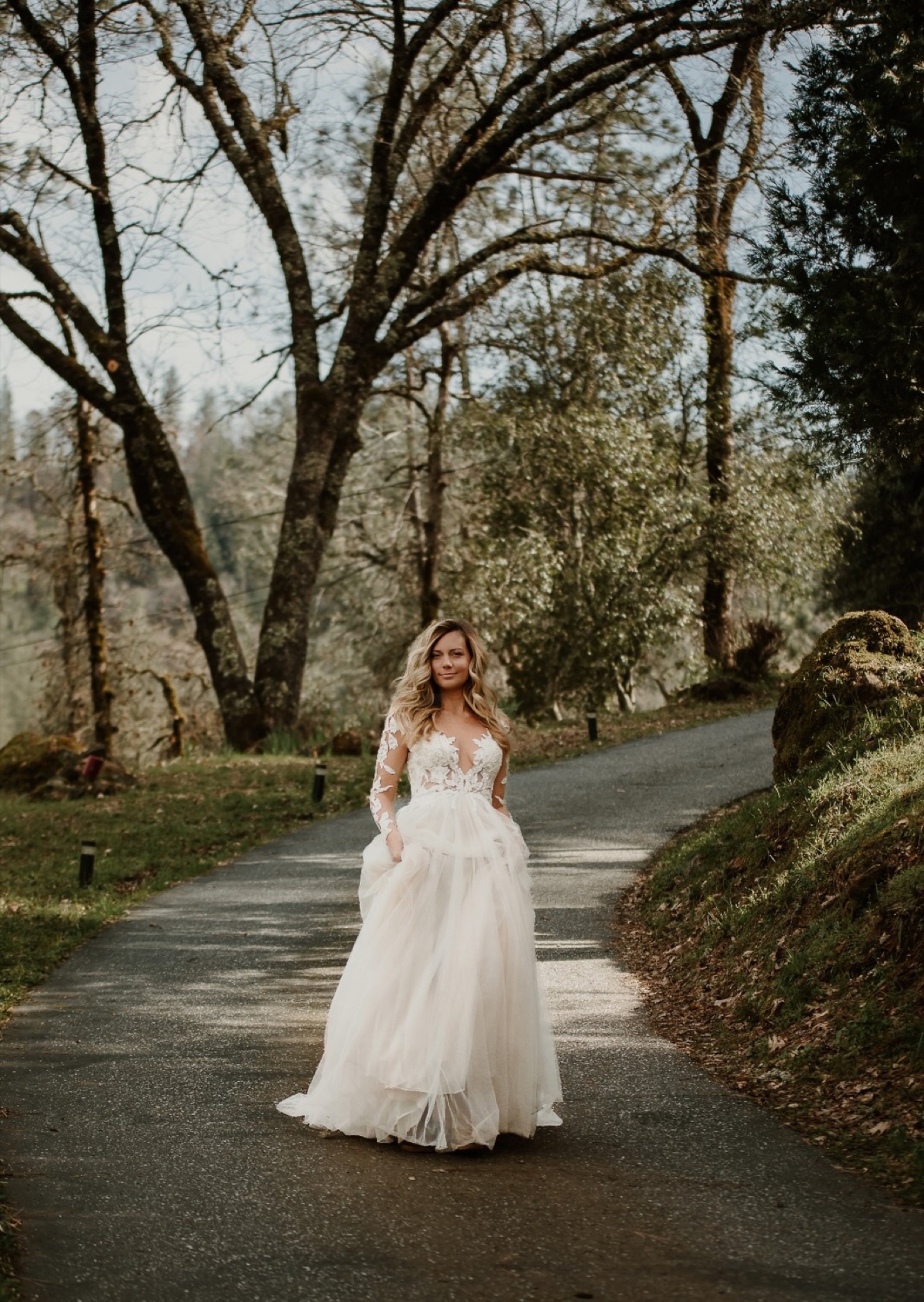 Bride standing on a tree-lined path in her wedding gown